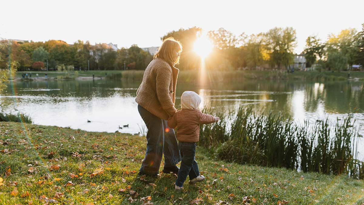 Mother and child walk by the pond